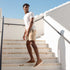 Man wearing tobacco brown leather Diego Everyday Sneakers and tan shorts walks down outdoor stone stairs.
