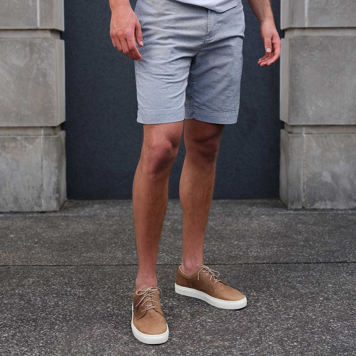 Pair of tobacco brown leather Diego Everyday Sneakers with white soles and tan laces worn with grey shorts.