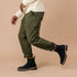 Pair of black leather Chelsea boots with lug soles worn with olive green pants and a cream sweater.