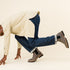 Pair of grey leather Chelsea boots with black elastic side panels and lug soles worn with cuffed blue jeans.