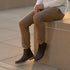Pair of black leather Marco Everyday Chelsea boots worn by a person sitting on a stone ledge.