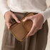 Hands holding an open, caramel-colored leather Remi Zip Wallet with card slots and a gold-toned zipper.