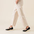 Pair of black leather Mary Jane flats worn by a person walking in tan trousers.