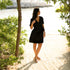 Woman in a black dress wearing almond leather Catalina Slide Sandals on a sandy path outdoors.